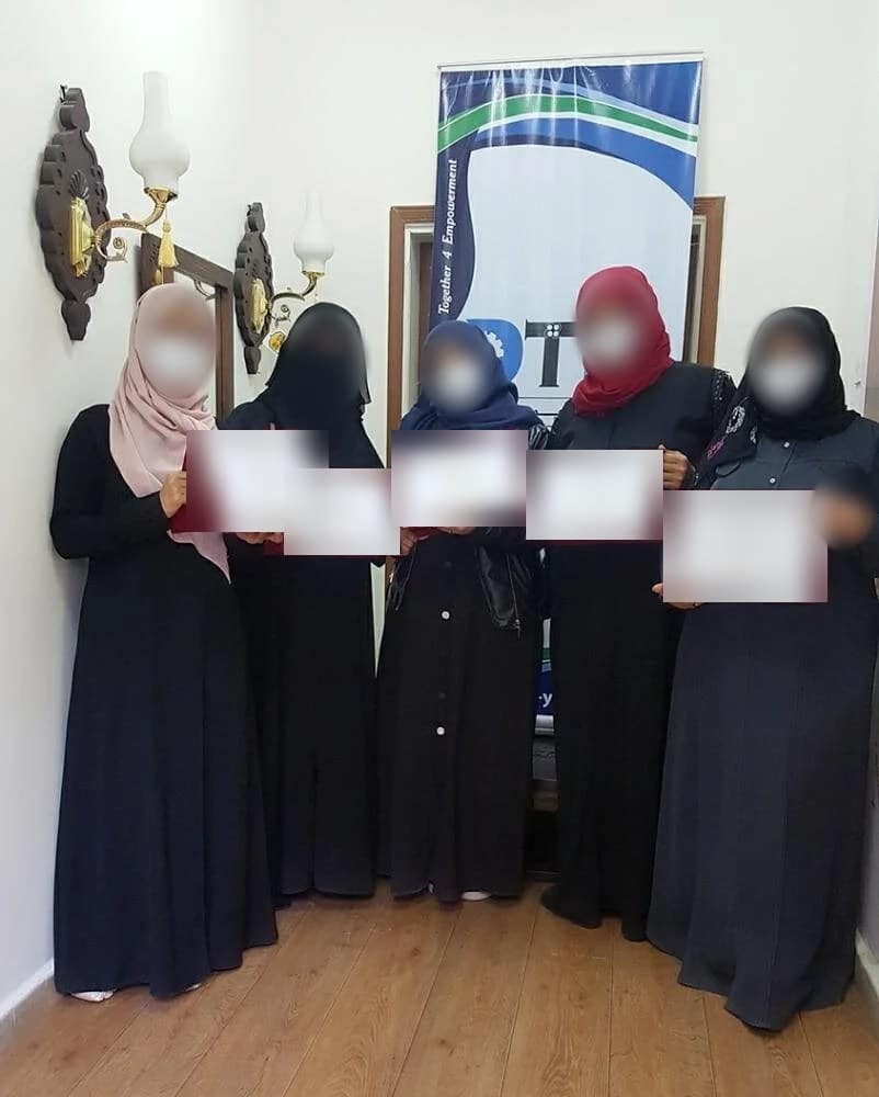 Five participants at a mini-MBA cohort in Sanaa holding certificates, names blurred for privacy