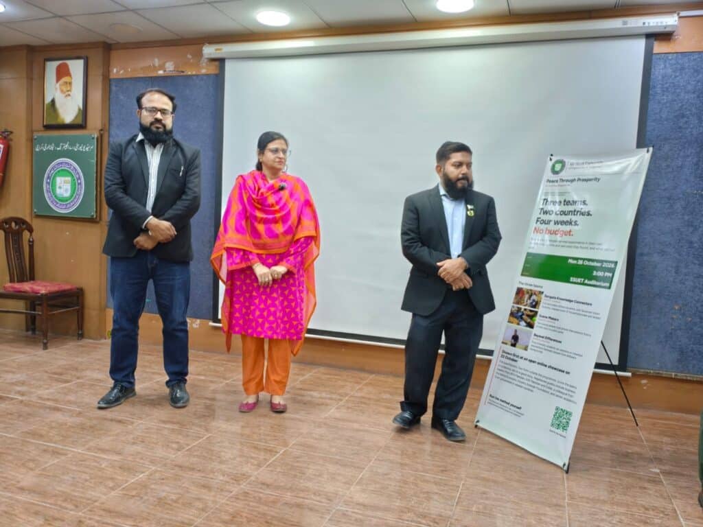 Professor Arsalan, Professor Sarfaraz and faculty head Shahina Noor on stage beside the Grassroots Internships standee at Sir Syed University, Karachi